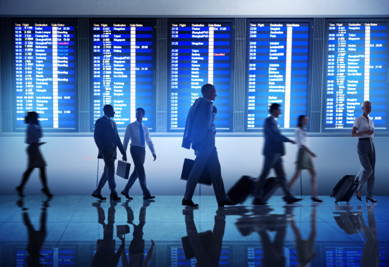 Varias personas caminando rápidamente frente a pantallas de datos, representando cómo las aerolíneas pueden aprovechar la analítica avanzada para detectar oportunidades invisibles a simple vista.
